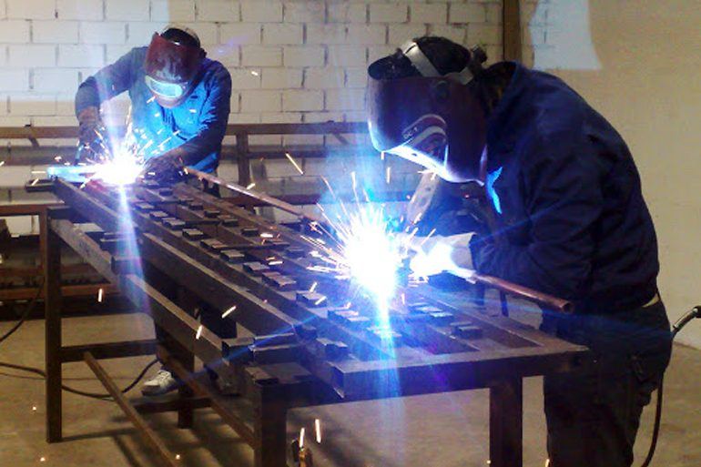 Dos soldadores de Hurbec trabajando sobre una estructura metálica en el taller